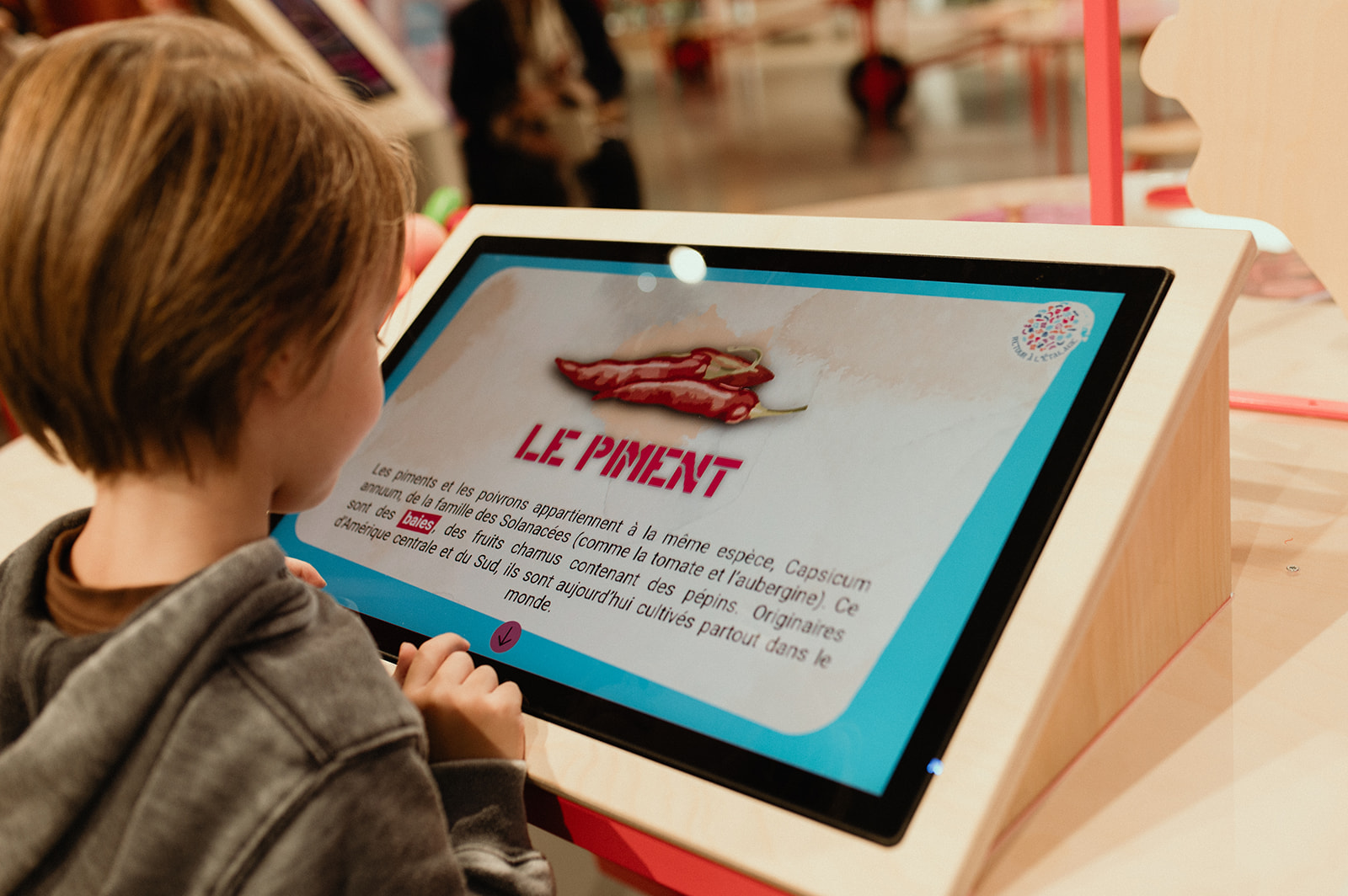 Photo d'un enfant posant un poid sur une balance lors d'une activité ludique de l'exposition graines